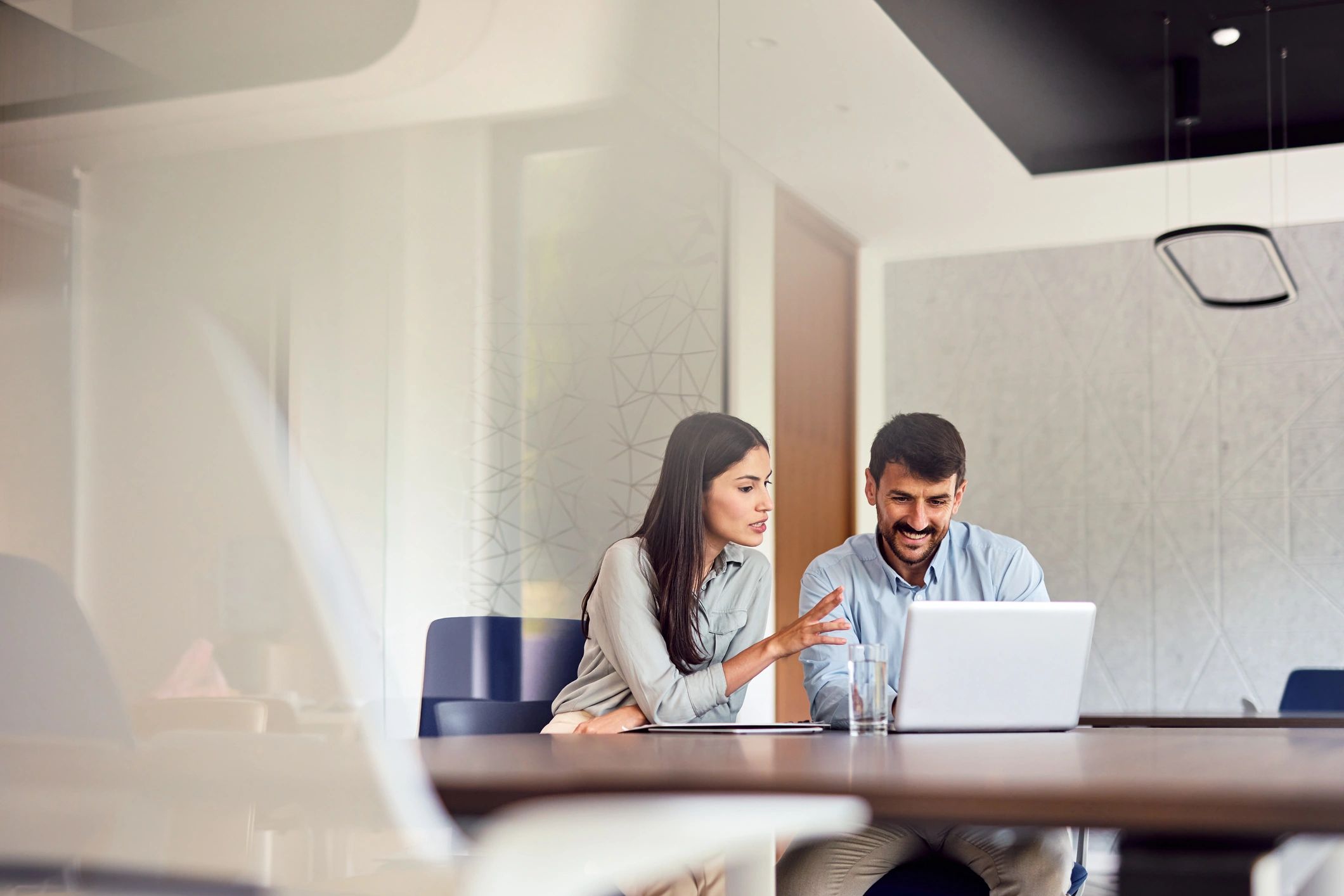 Two professionals reviewing work on a laptop